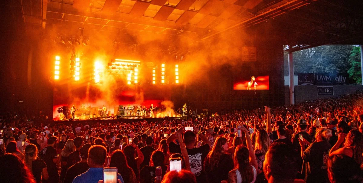 Concert stage with full lighting rig and packed crowd at night