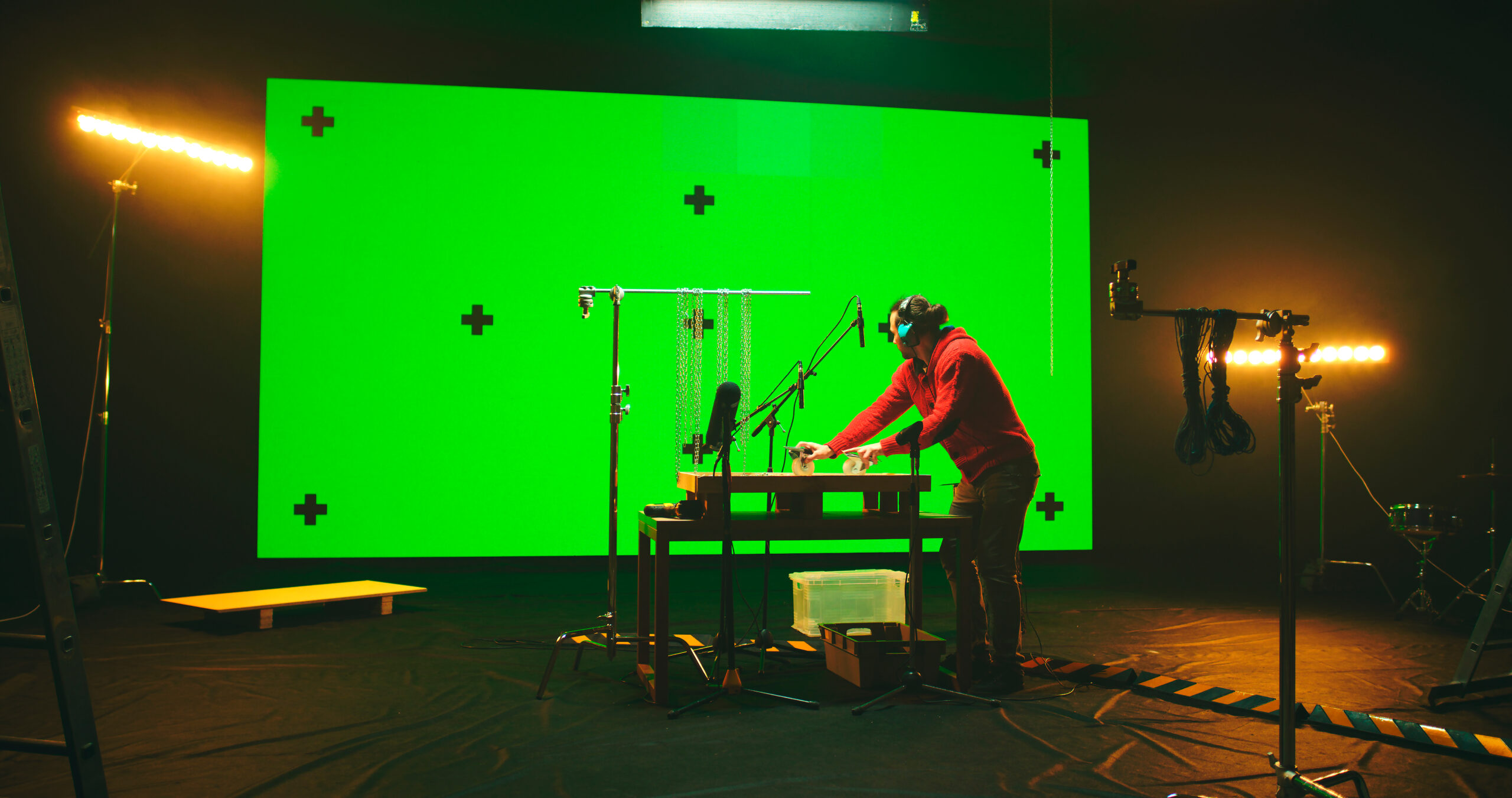 Technician working in a studio with a green screen and production monitors